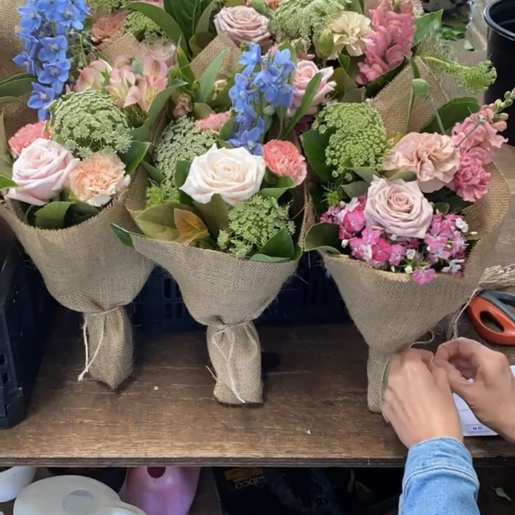 Florist tying message tag onto bouquet at Little Flowers HQ